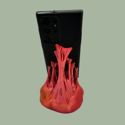 3D printed phone stand in a random colour, designed to look like your phone is being pulled out of something sticky