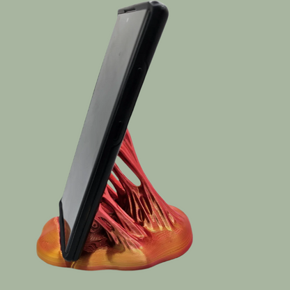 3D printed phone stand in a random colour, designed to look like your phone is being pulled out of something sticky