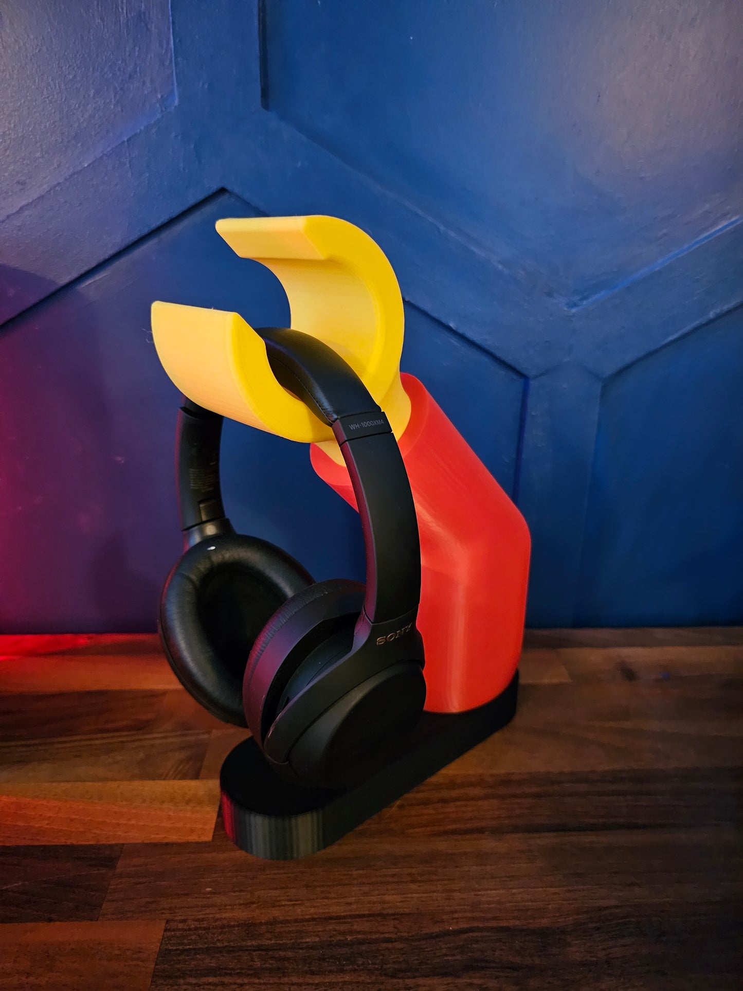 3D printed block style arm in various colours, with black base for wall or freestanding mounting, with chunky yellow hand to hold headphones or coats