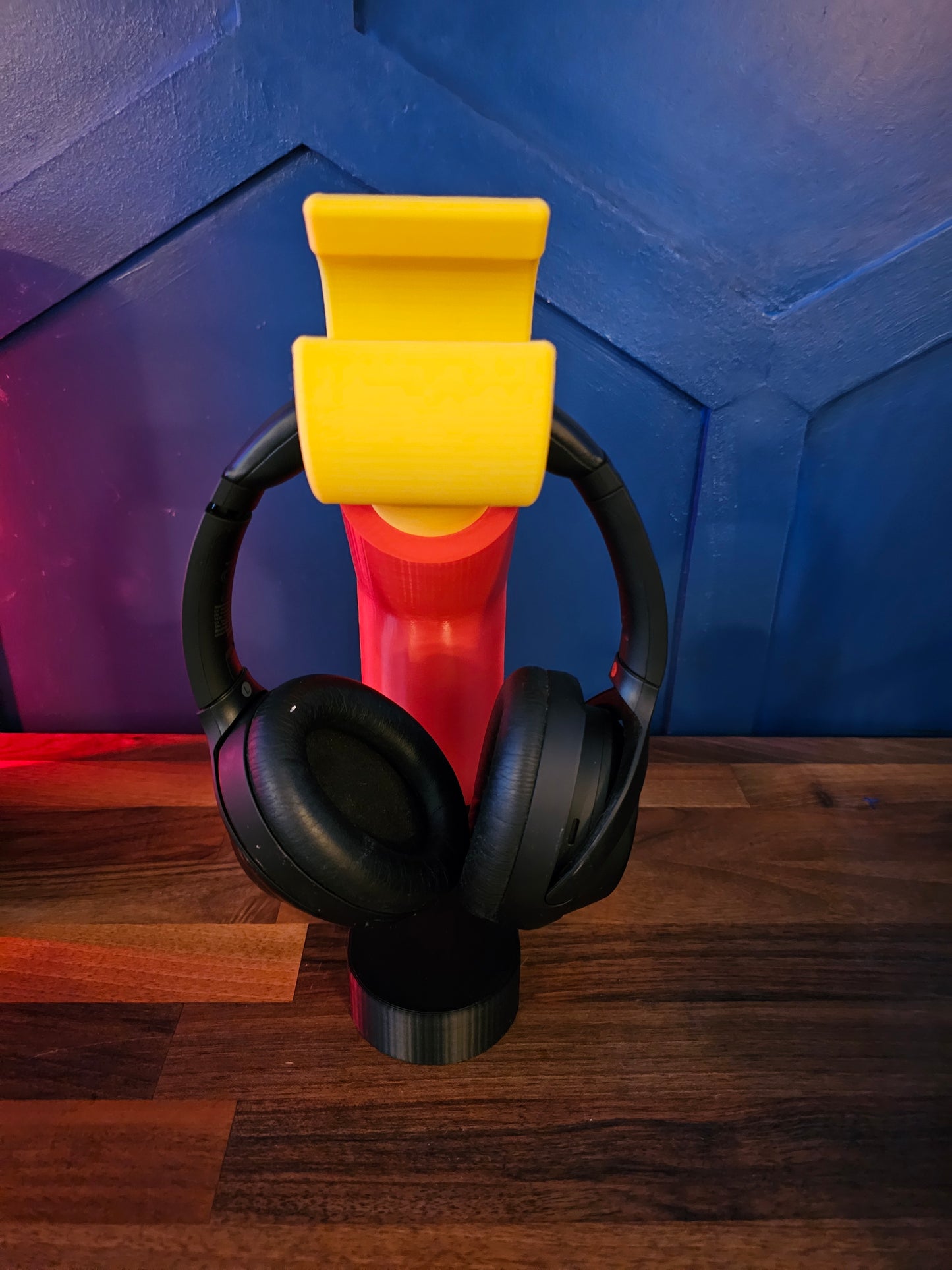 3D printed block style arm in various colours, with black base for wall or freestanding mounting, with chunky yellow hand to hold headphones or coats