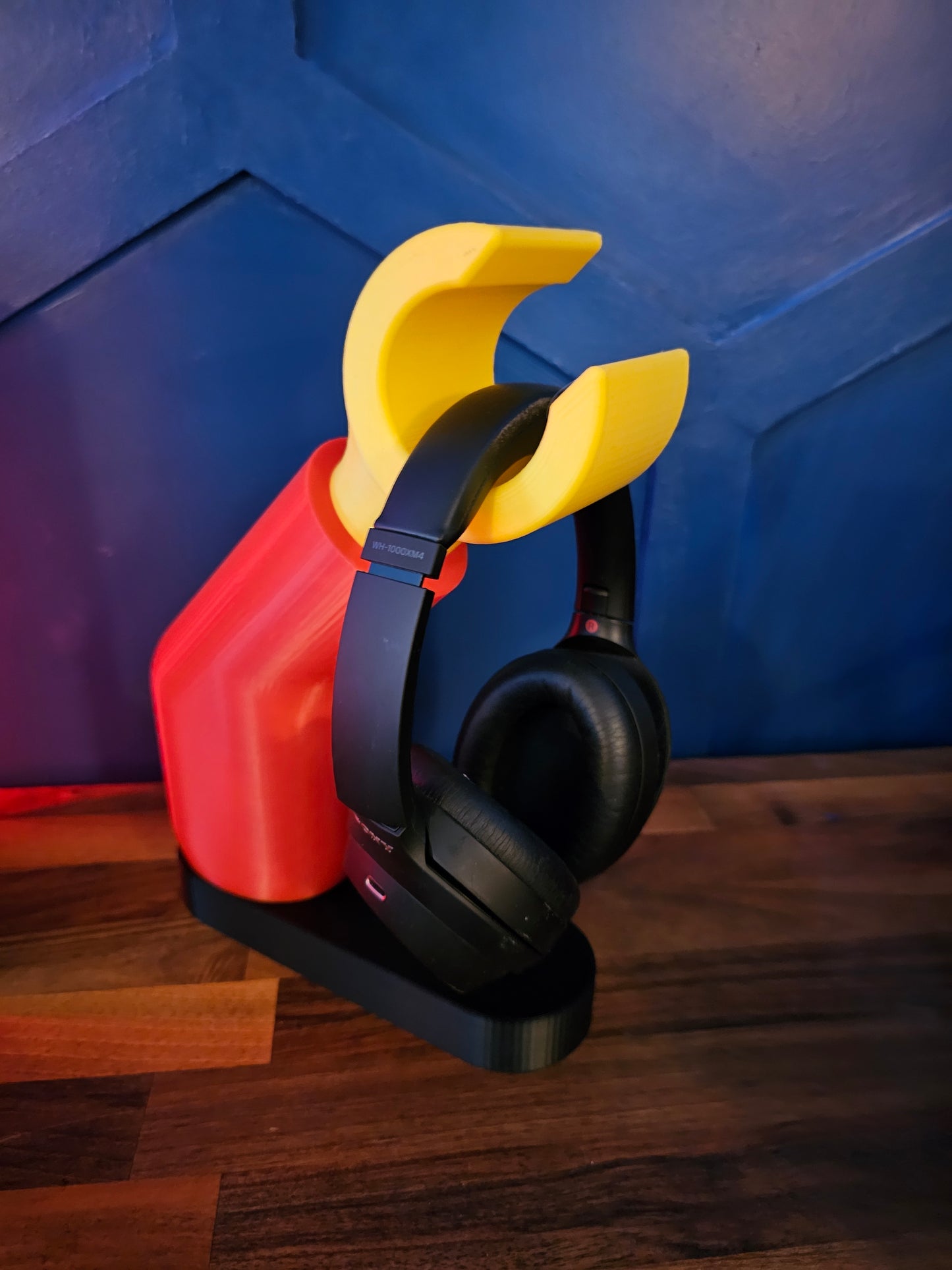 3D printed block style arm in various colours, with black base for wall or freestanding mounting, with chunky yellow hand to hold headphones or coats