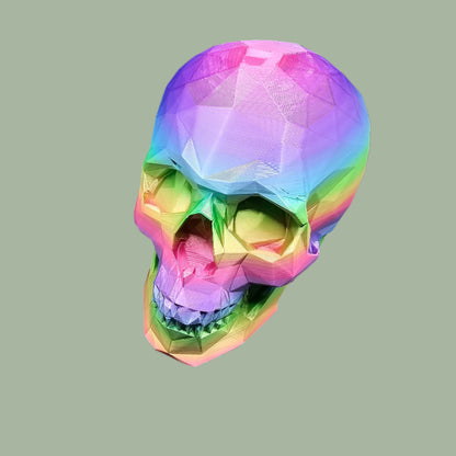 3D-printed low-poly rainbow skull figurine, uniquely coloured with a vibrant gradient. Handmade in the UK, 12cm tall, and perfect for modern home decor or gothic-inspired interiors