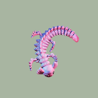 3D-printed articulated axolotl figurine in a shiny, colour-shifting finish. Handmade in the UK, approx. 21cm long, with a flexible, wiggly body. Perfect for axolotl lovers and fidget toy fans