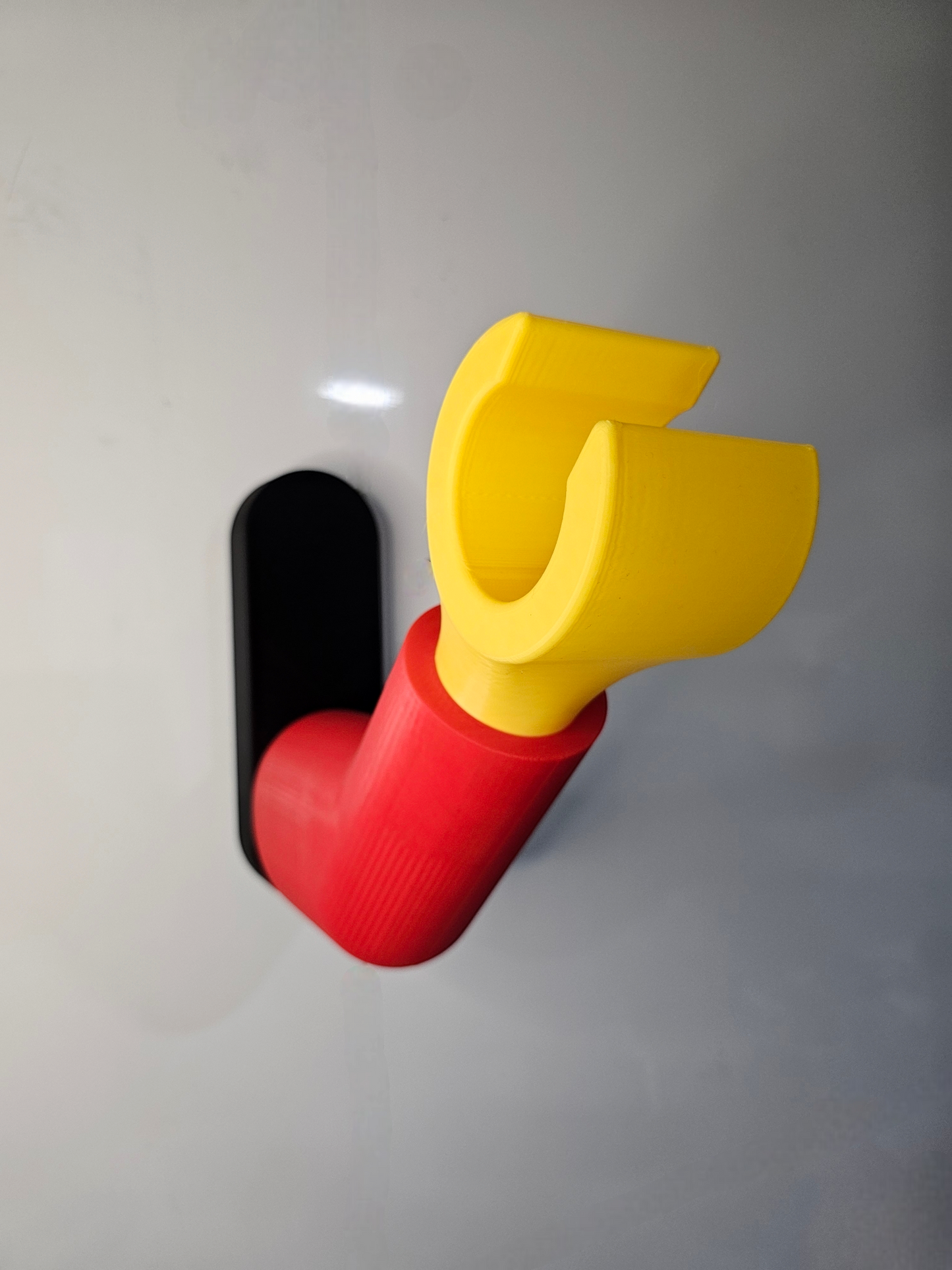 3D printed block style arm in various colours, with black base for wall or freestanding mounting, with chunky yellow hand to hold headphones or coats