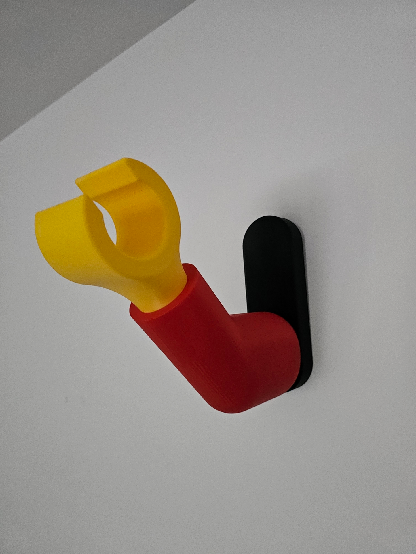 3D printed block style arm in various colours, with black base for wall or freestanding mounting, with chunky yellow hand to hold headphones or coats