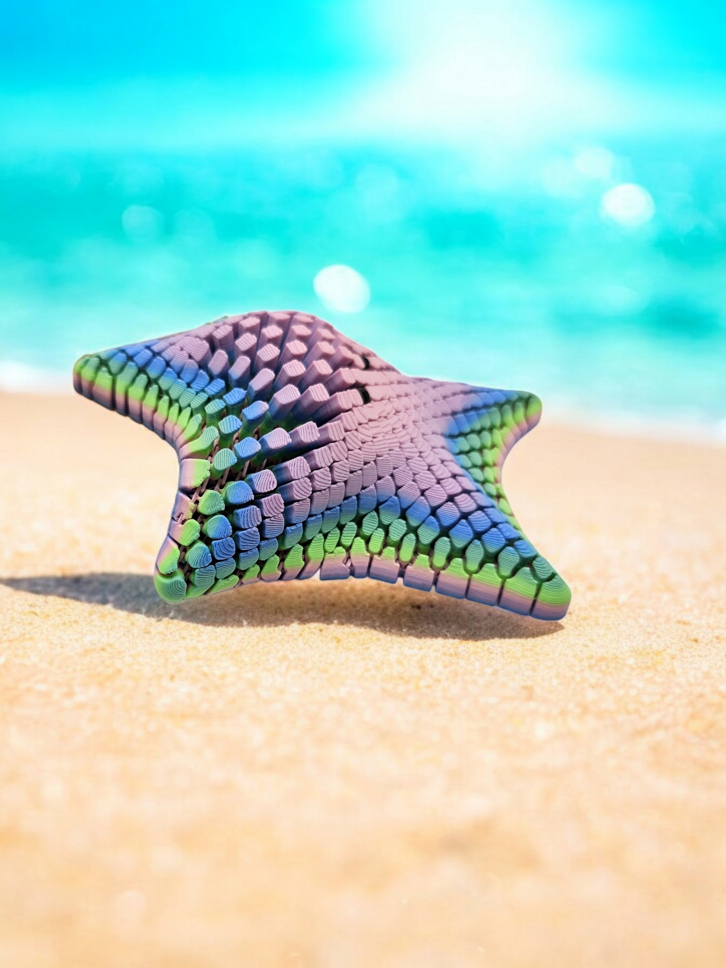 3D printed mesh articulated starfish with black eyes in a pastel rainbow colour