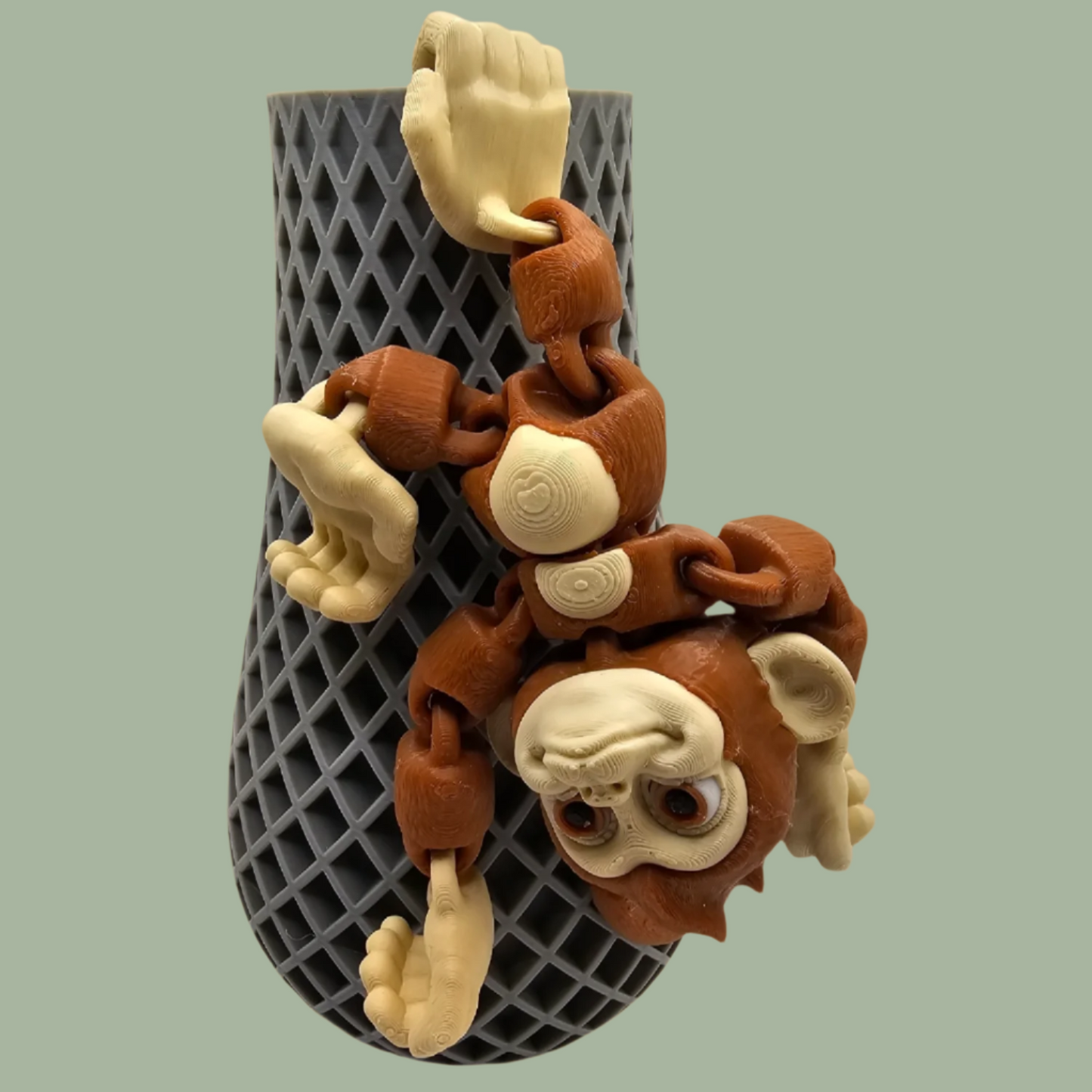 3D printed articulated monkey with hook tail, hook hands, and hook feet hanging from a pot