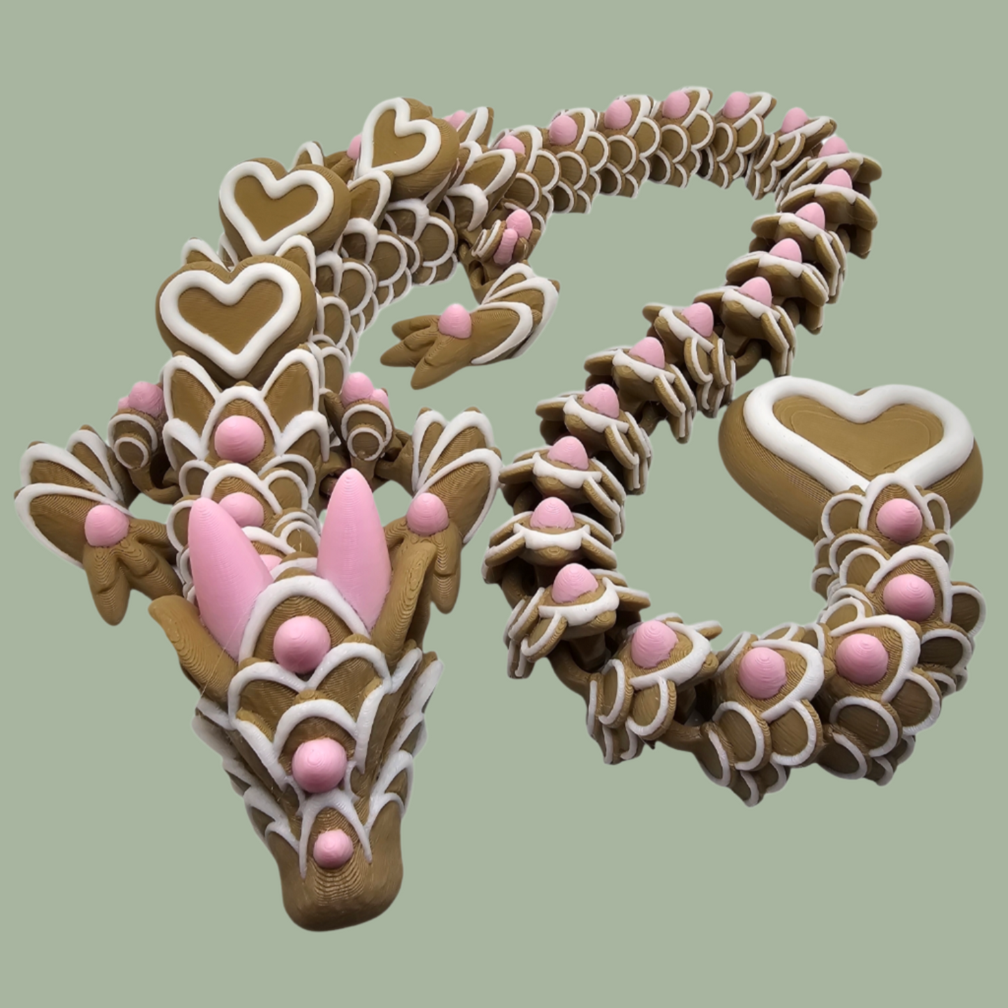 3D printed cookie style articulated dragon with pink and white icing details