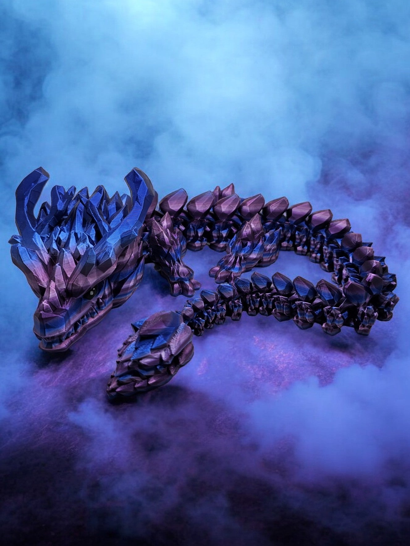 3D printed articulated dragon with large horns, in a purple/pink/blue colour